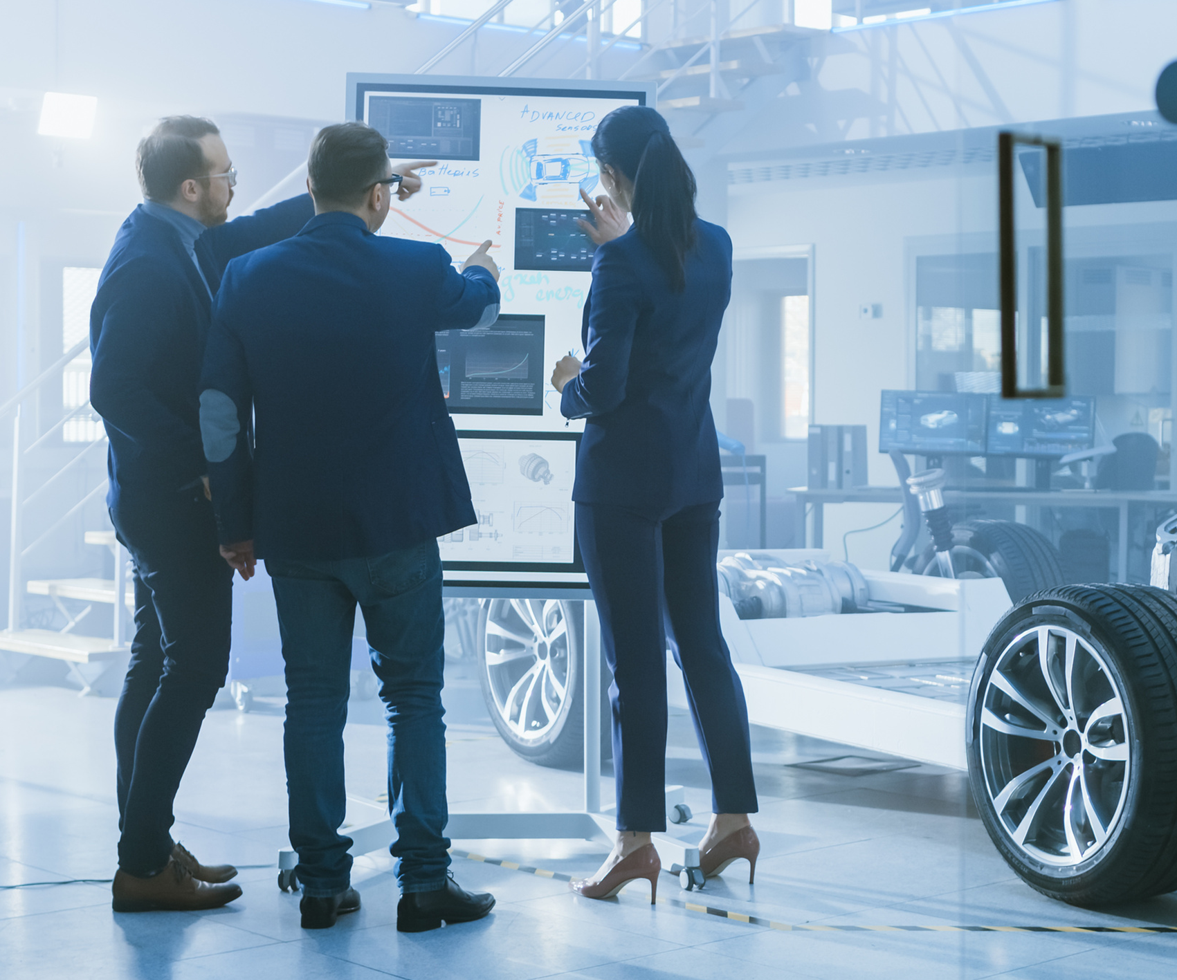 three people looking at a board of vehicle diagrams